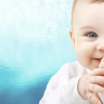 a baby with blue eyes and a hand on its mouth