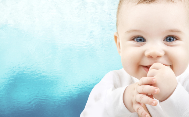 a baby with blue eyes and a hand on its mouth