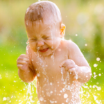 Kleinkind im Garten spielt mit Wasser