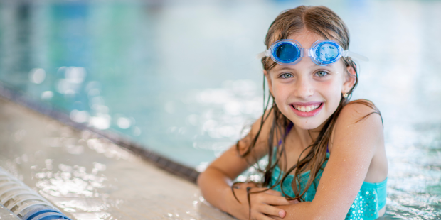 Mädchen in Badeklamotten posiert während dem Schwimmunterricht zur Kamera Mädchen in Badeklamotten posiert während dem Schwimmunterricht zur Kamera