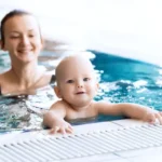 Mutter-lehrt-Baby-schwimmen-in-einem-Schwimmbad