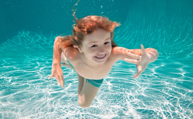 Junge Schwimmt unter Wasser mit offenen Augen und freut sich