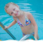Mädchen am Pool schaut direkt in die Kamera und lächelt