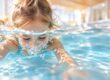 Kind übt das Ausatmen unter Wasser beim Schwimmenlernen